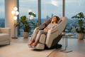 Person fully reclined and relaxing in cream and grey zero gravity full body massage chair in modern living room